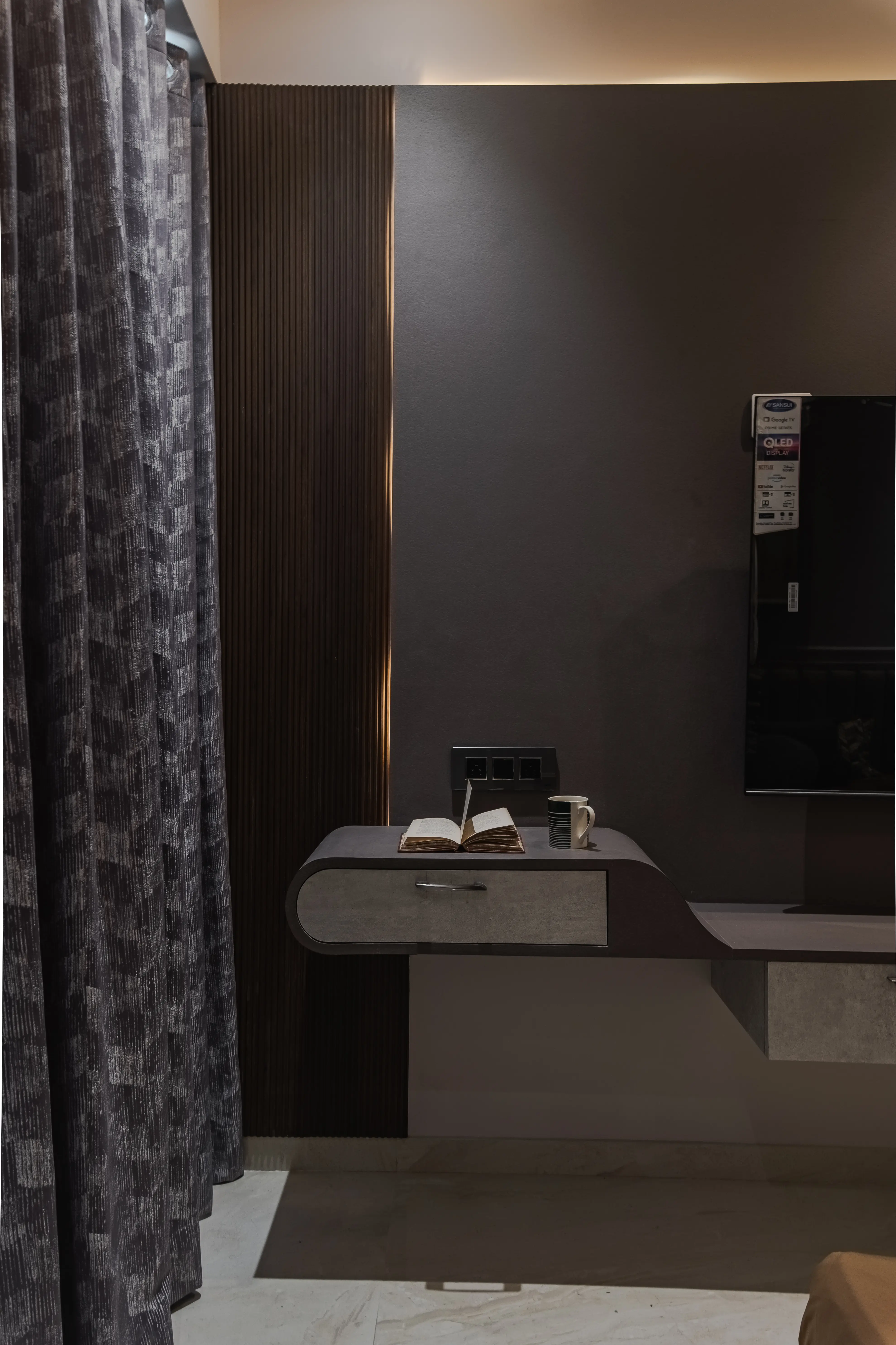 Modern bedroom features flat screen TV, desk with open book and coffee cup, interior by Archnine Design Studio